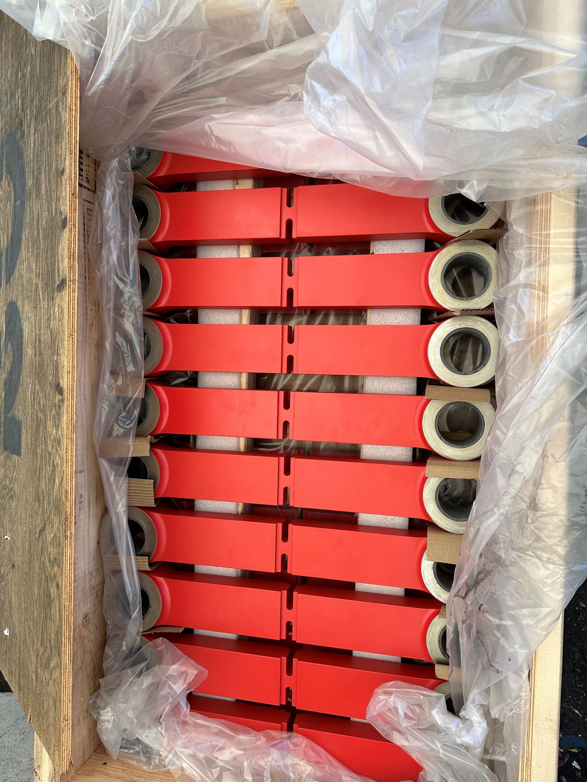 Caisse en bois contenant des objets rectangulaires rouges empilés avec des cylindres blancs et noirs.