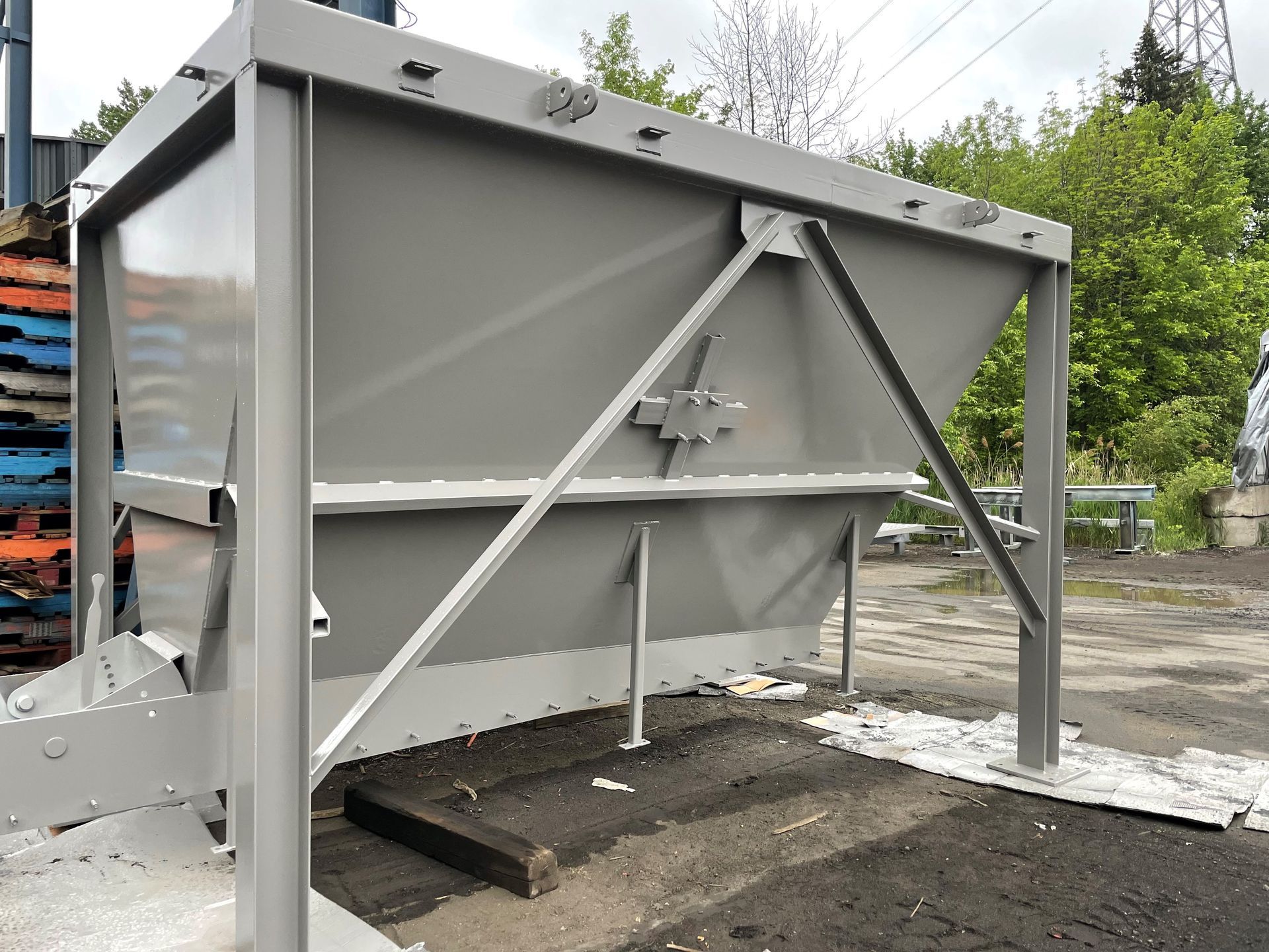 Trémie industrielle en métal gris sur une surface pavée; à l'extérieur.