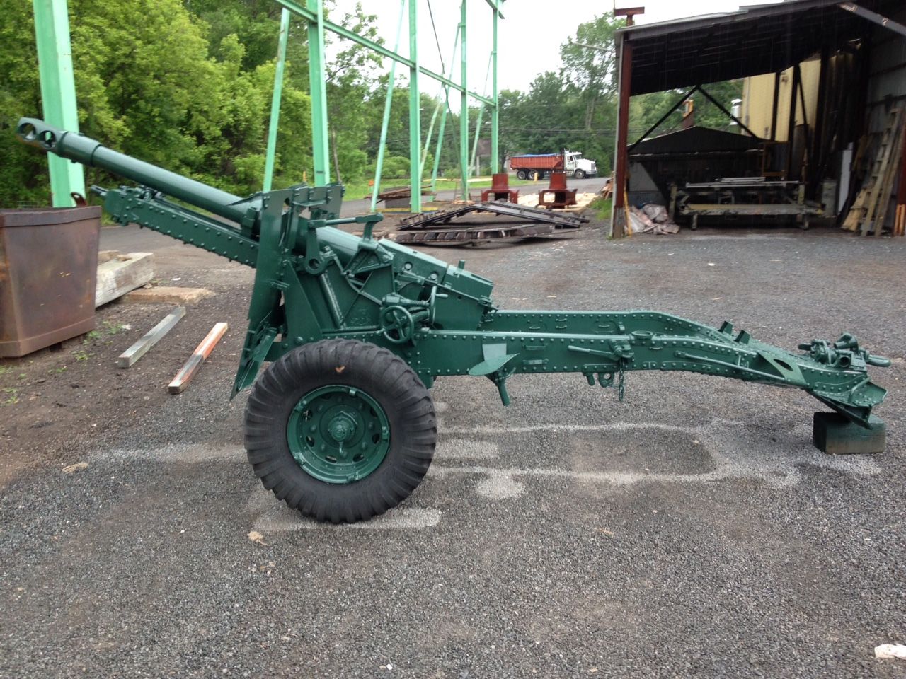 Pièce d'artillerie militaire verte, garée sur l'asphalte, à l'extérieur.