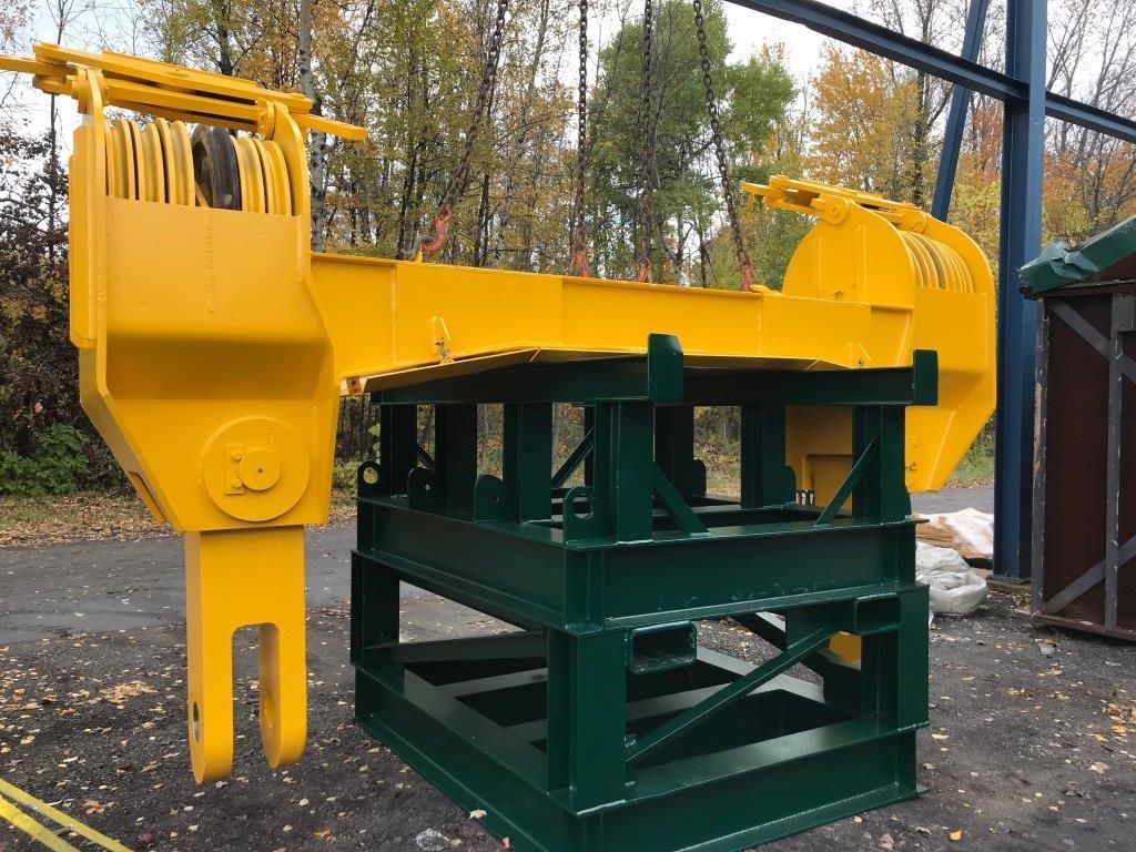 Bras de grue jaune sur un cadre en métal vert foncé, à l'extérieur.