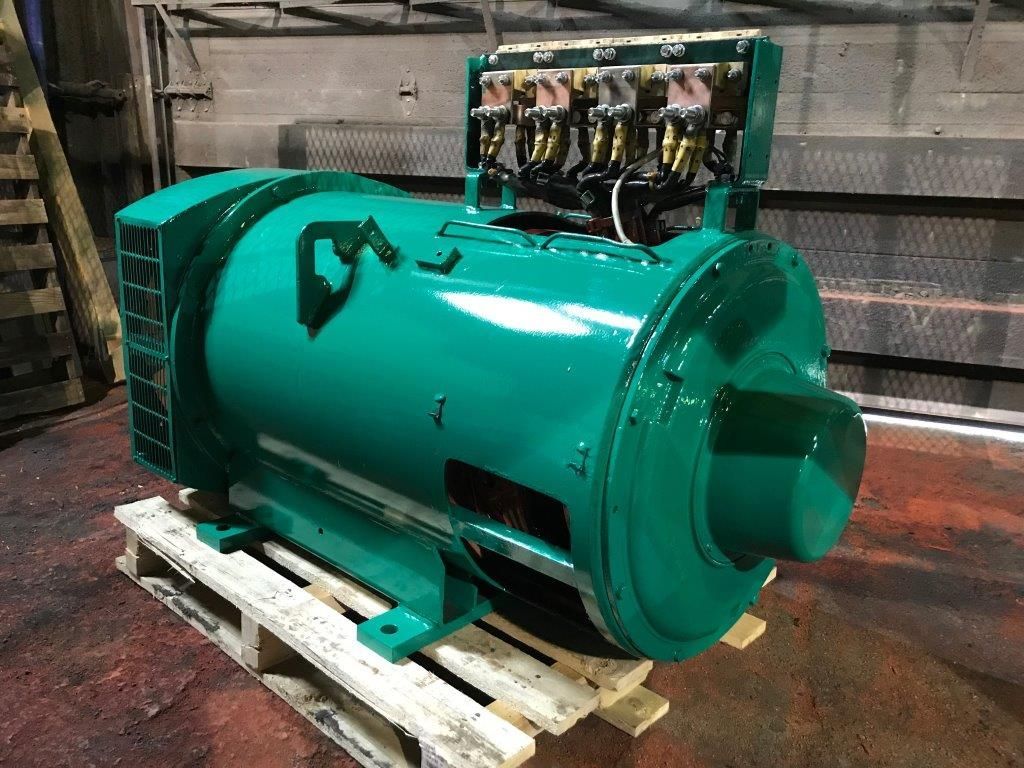 Générateur industriel vert sur une palette en bois ; connexions électriques visibles sur le dessus.