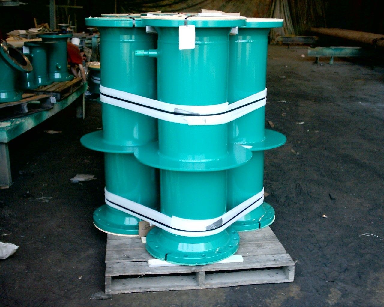 Six tuyaux industriels verts empilés et attachés ensemble sur une palette.