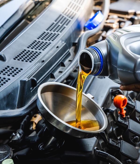 A person is pouring oil into a car engine.