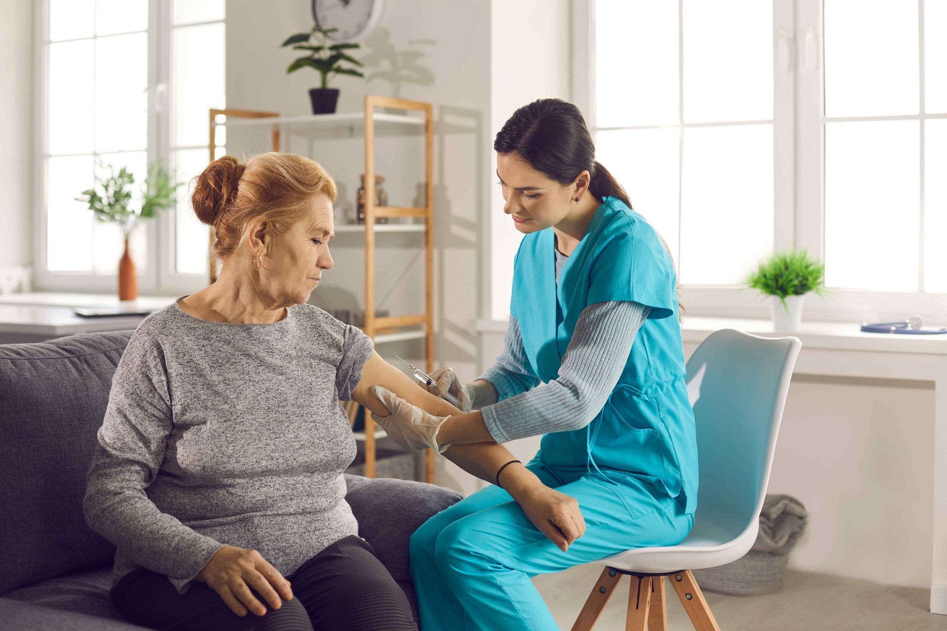 A nurse is giving an elderly woman an injection in her arm.
