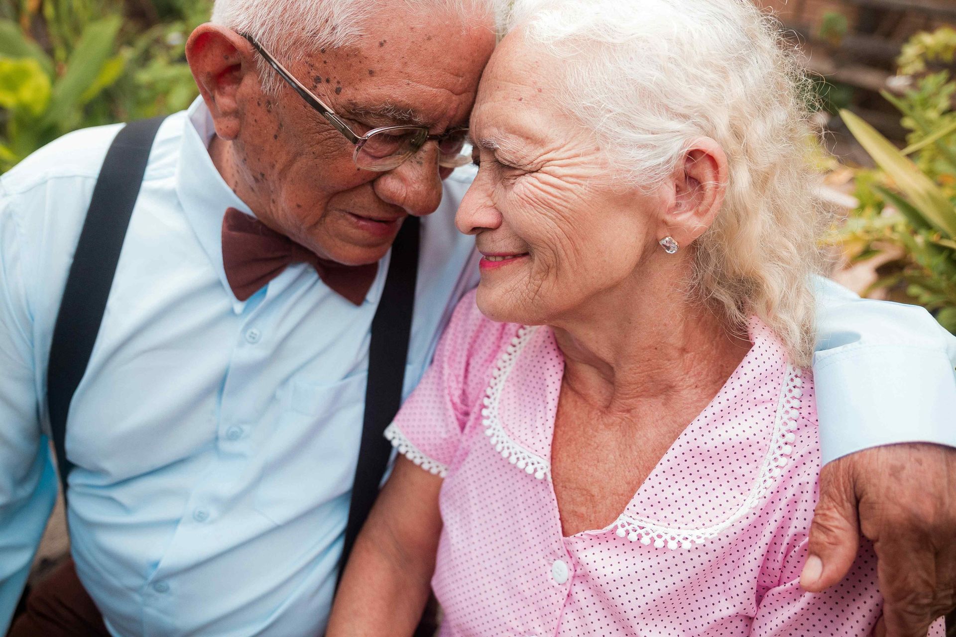 An elderly couple is sitting next to each other and looking at each other.