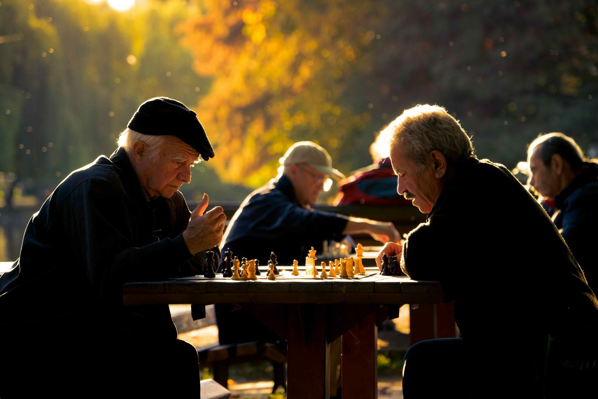 A group of men are playing chess at a picnic table.