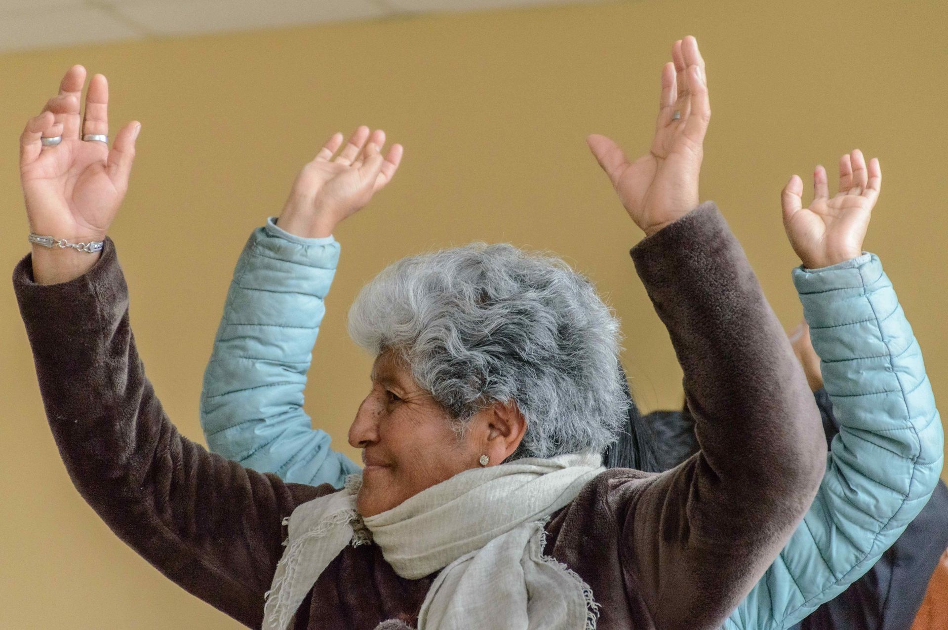 A woman with gray hair is raising her hands in the air