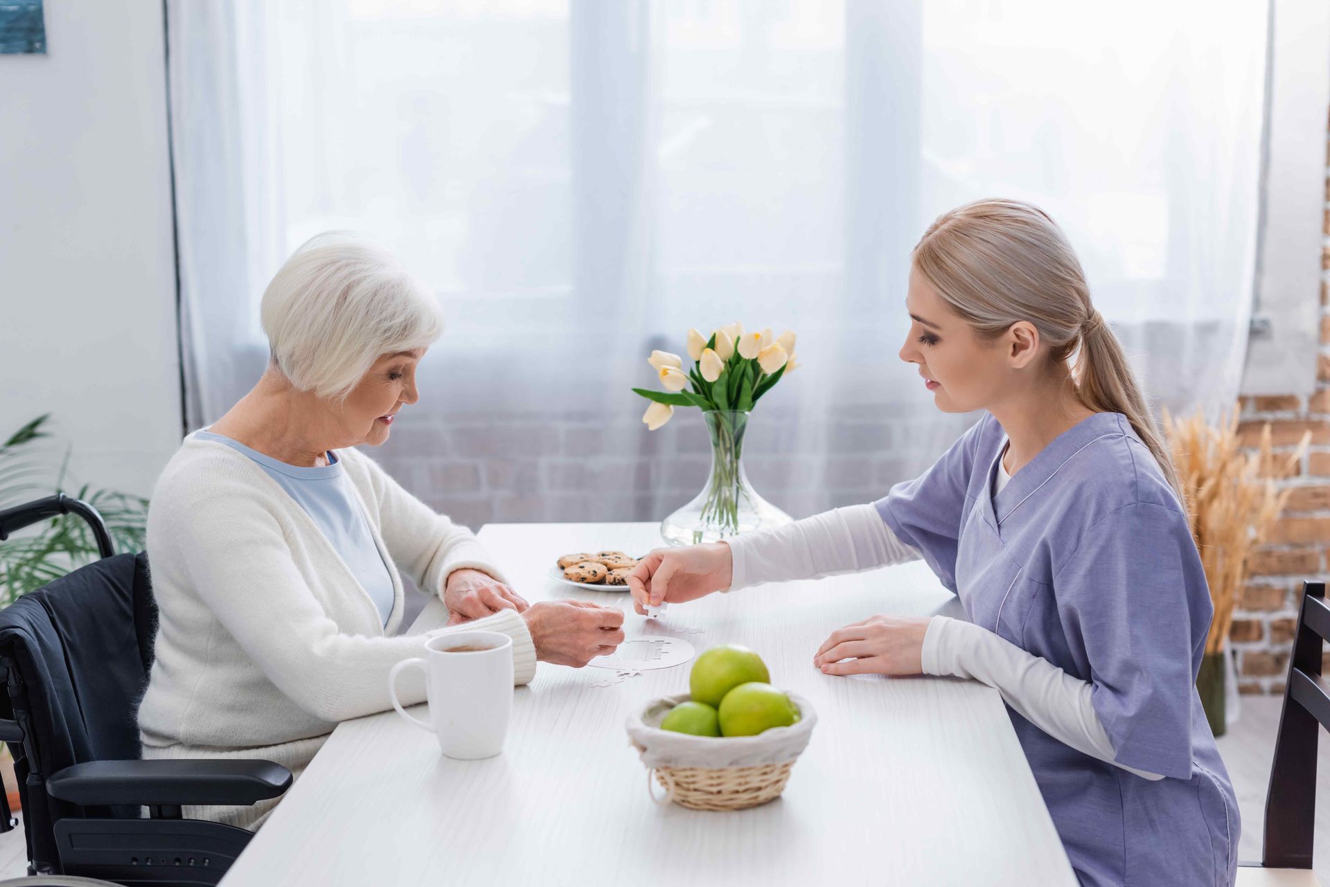 A nurse is feeding an elderly woman at a table.