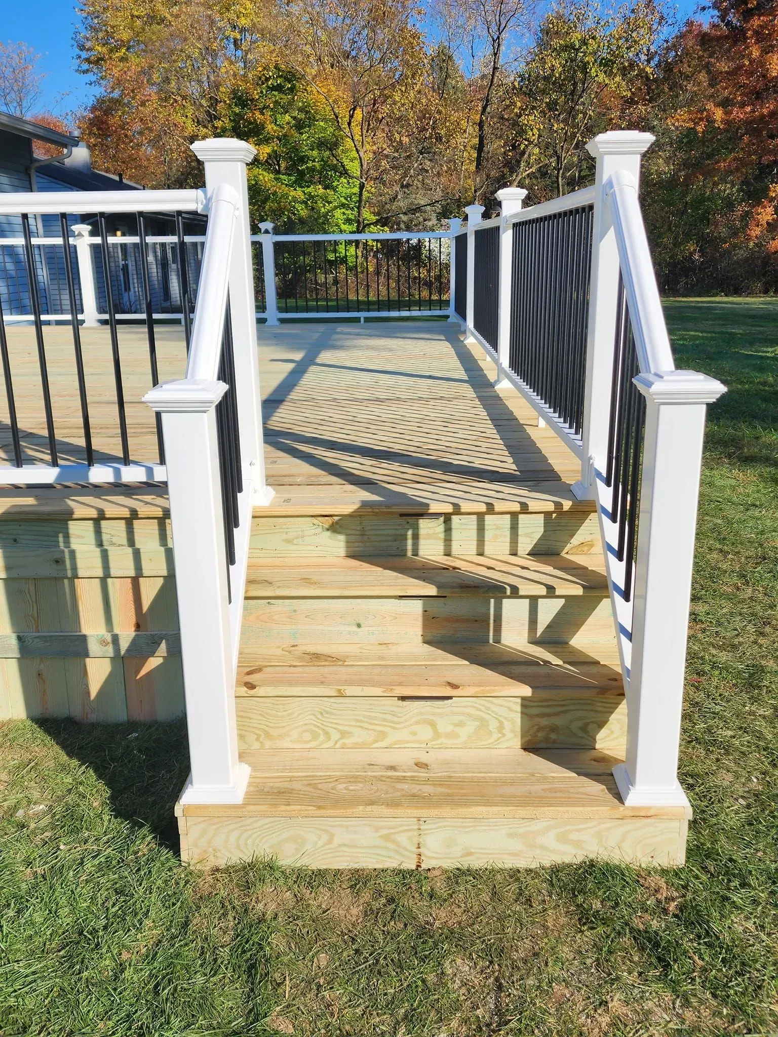 A wooden deck with stairs leading up to it and a white railing.