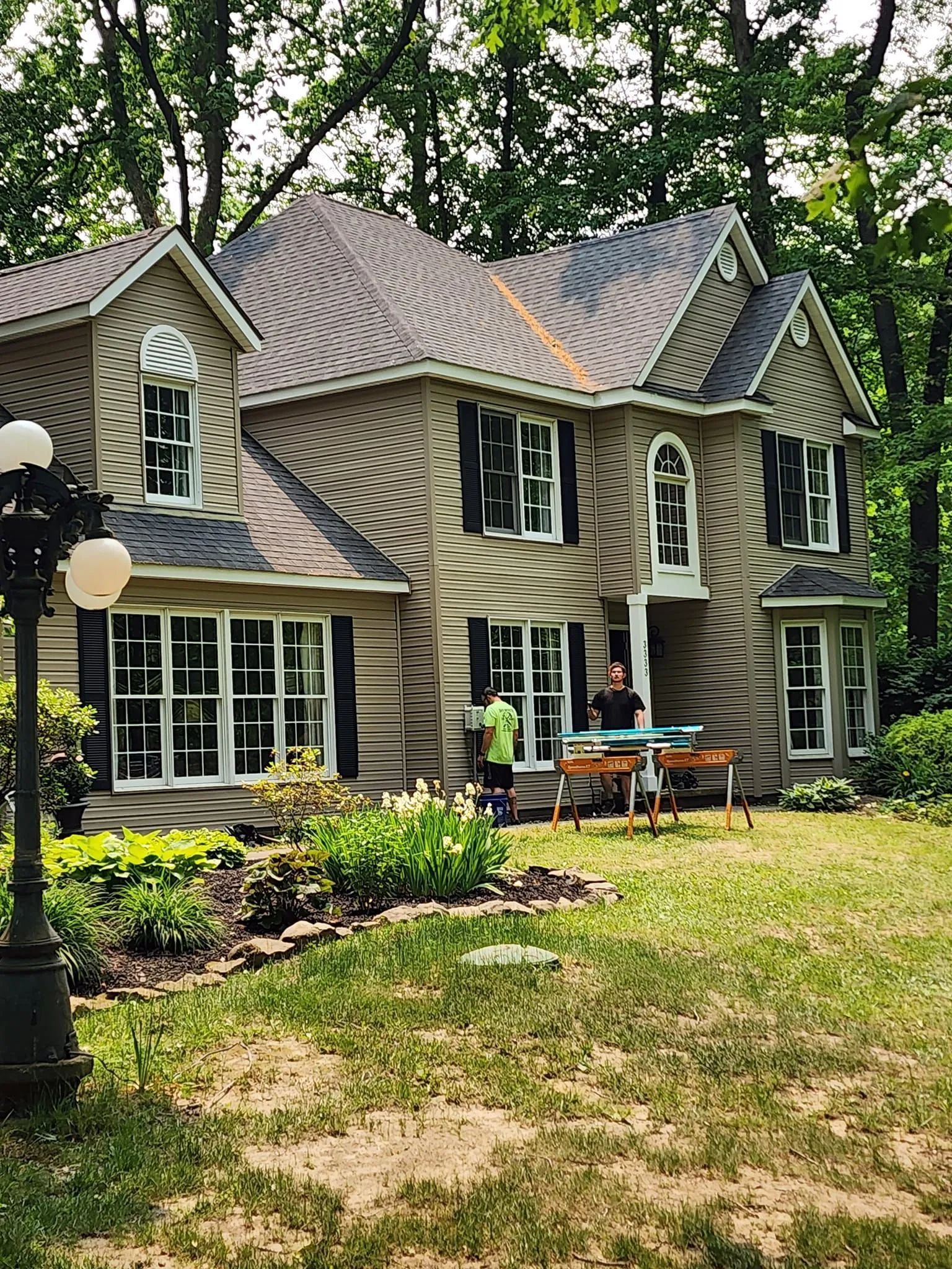 Two-story house with shutters. People load furniture onto a truck in front of the house.