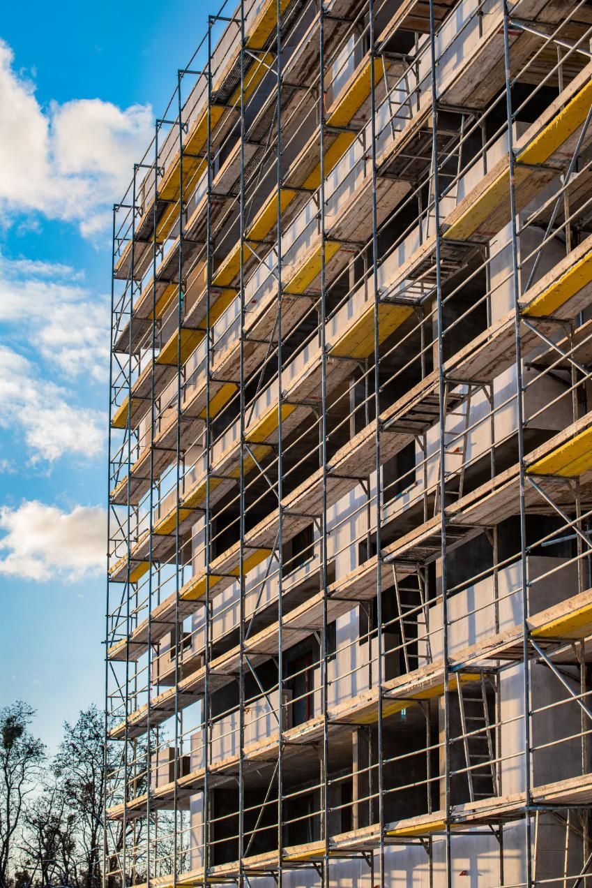 Scaffolding surrounds a building under construction, blue sky in background.
