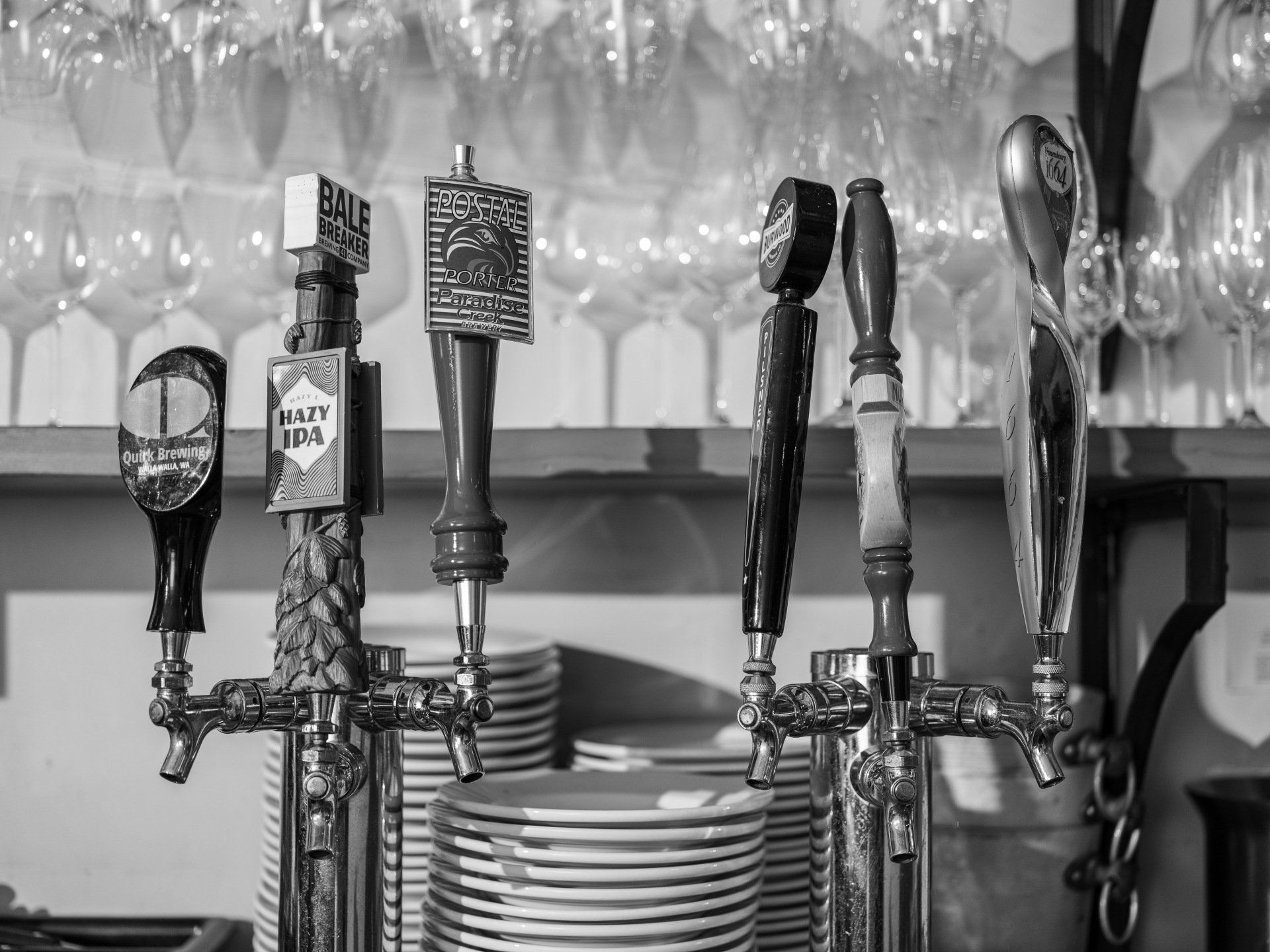 A black and white photo of beer taps in a bar.