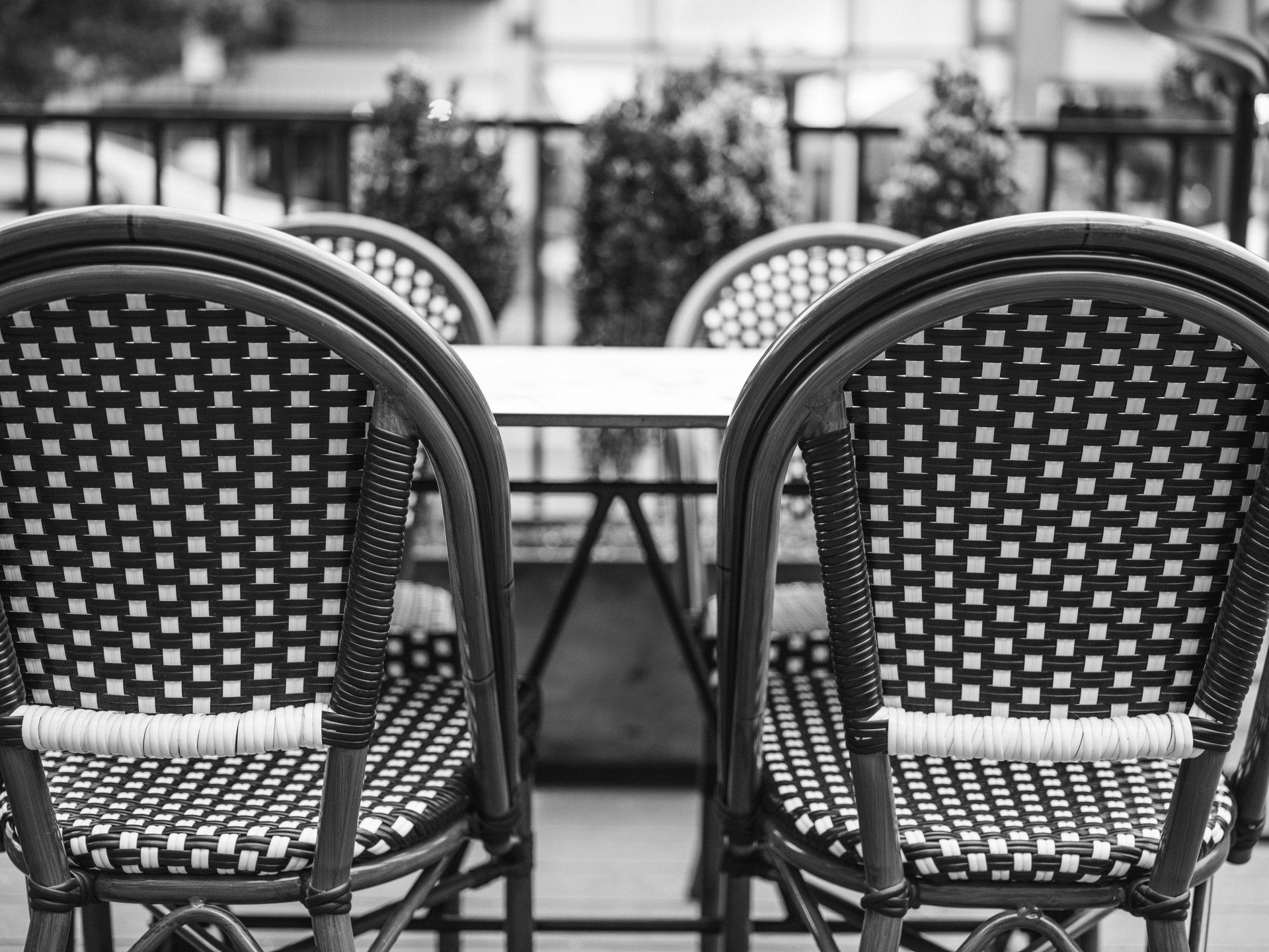A black and white photo of a table and chairs on a balcony.