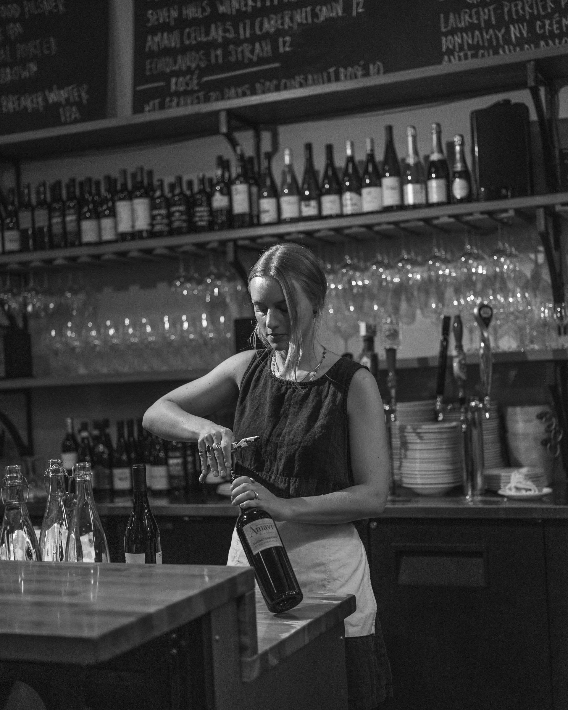 A woman is pouring a bottle of wine into a glass