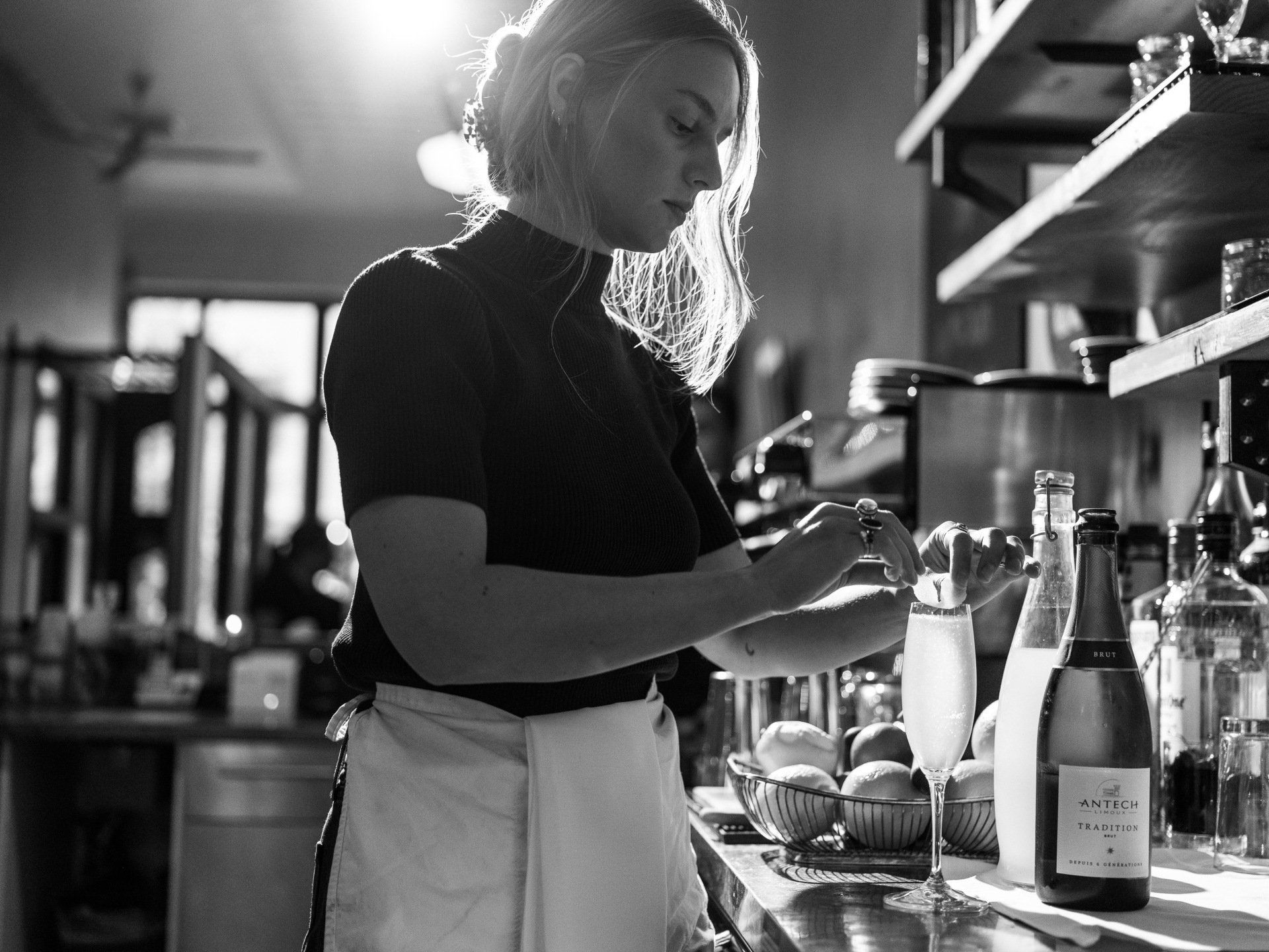A woman is standing in a kitchen preparing food.