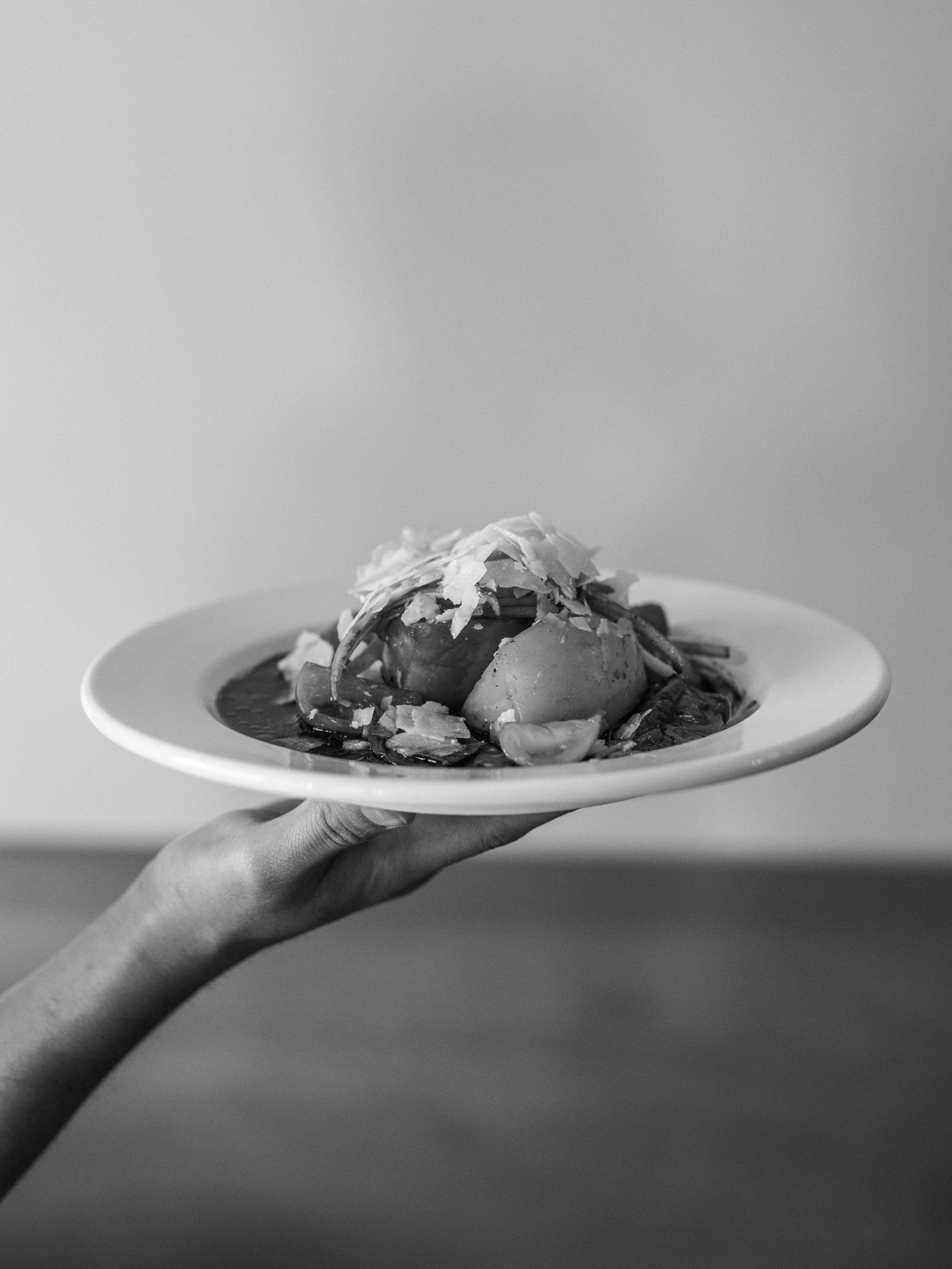 A black and white photo of a person holding a plate of food.