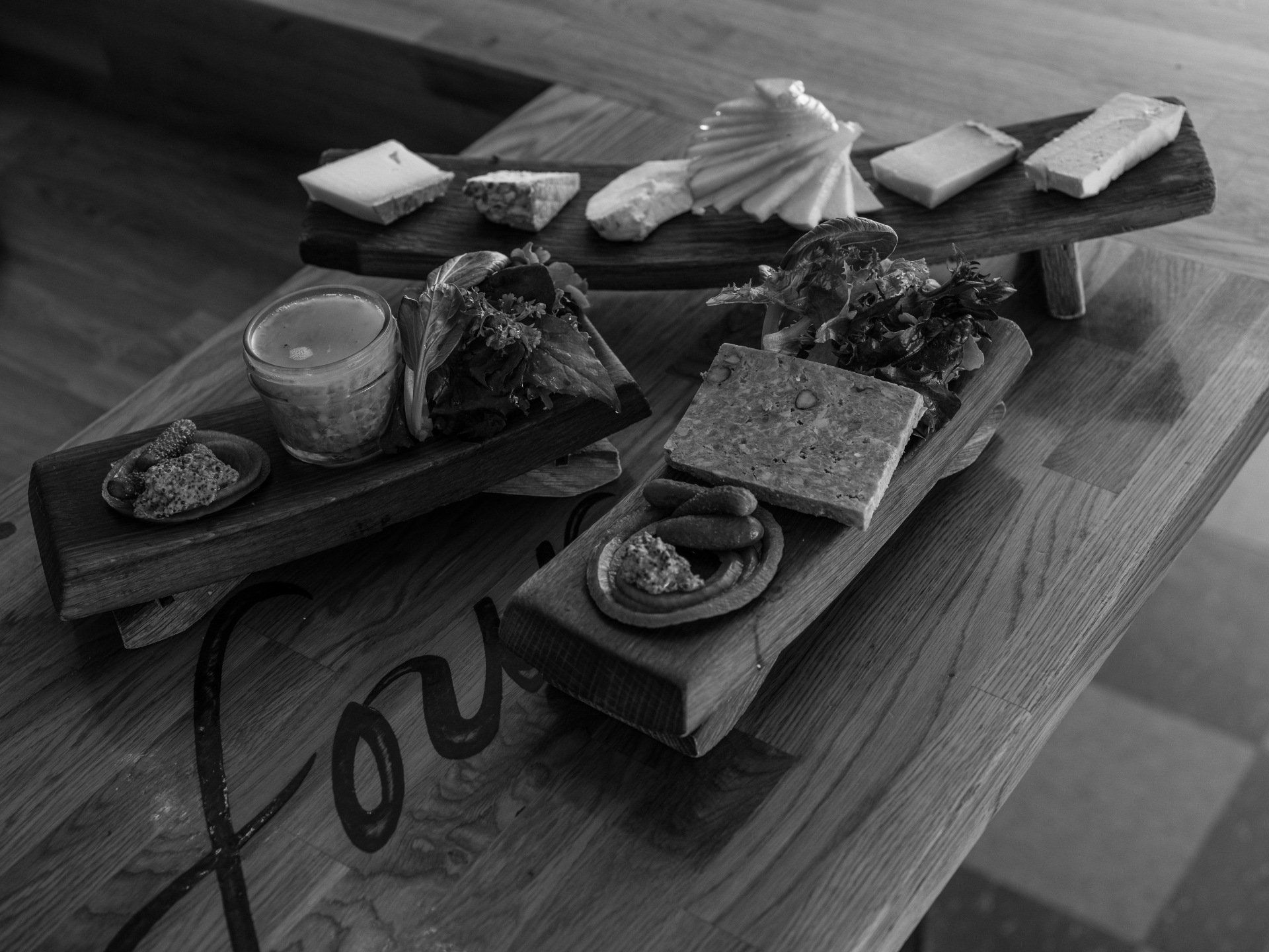 A black and white photo of three trays of food on a wooden table.