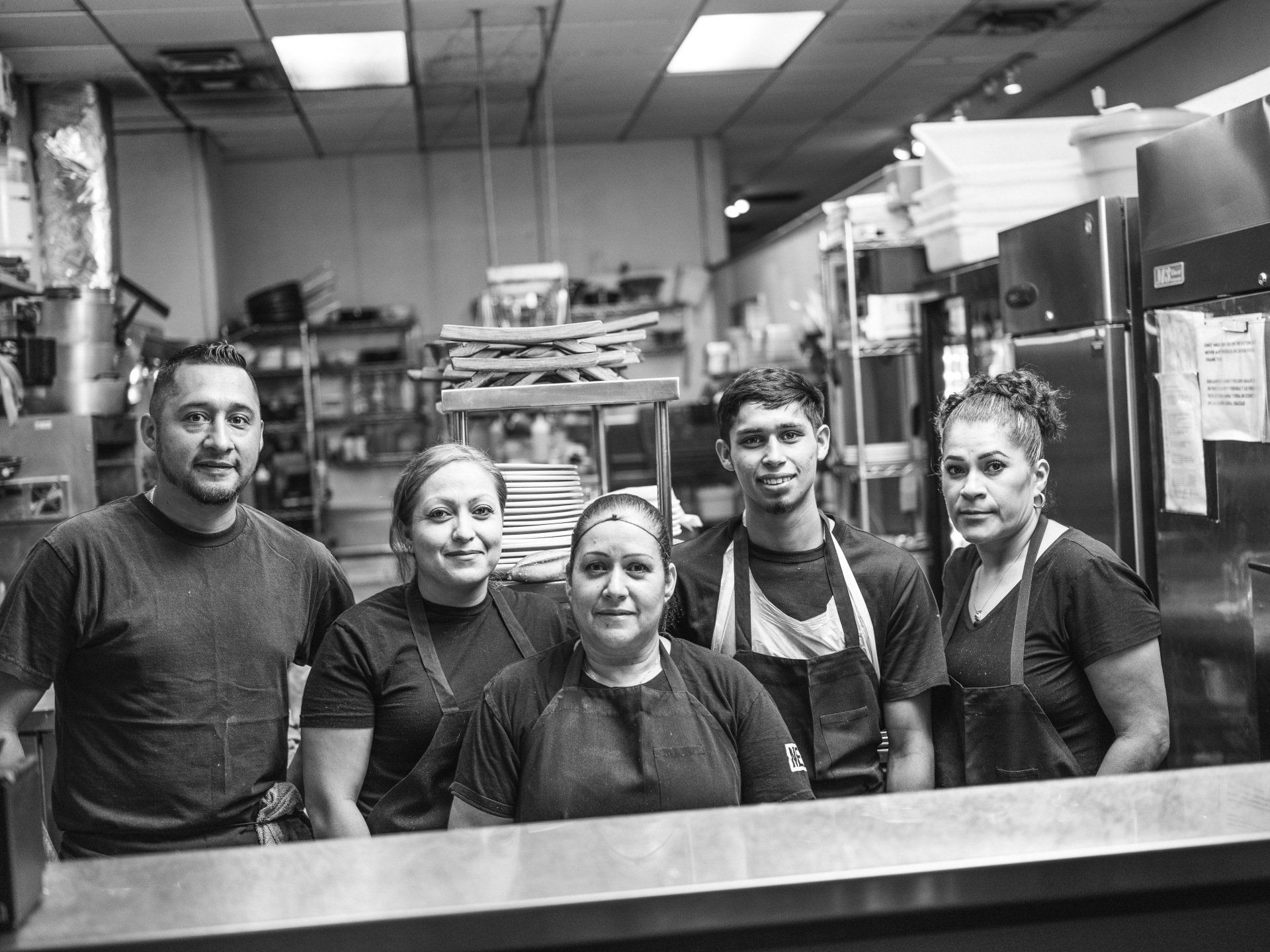 A group of people are posing for a picture in a kitchen.