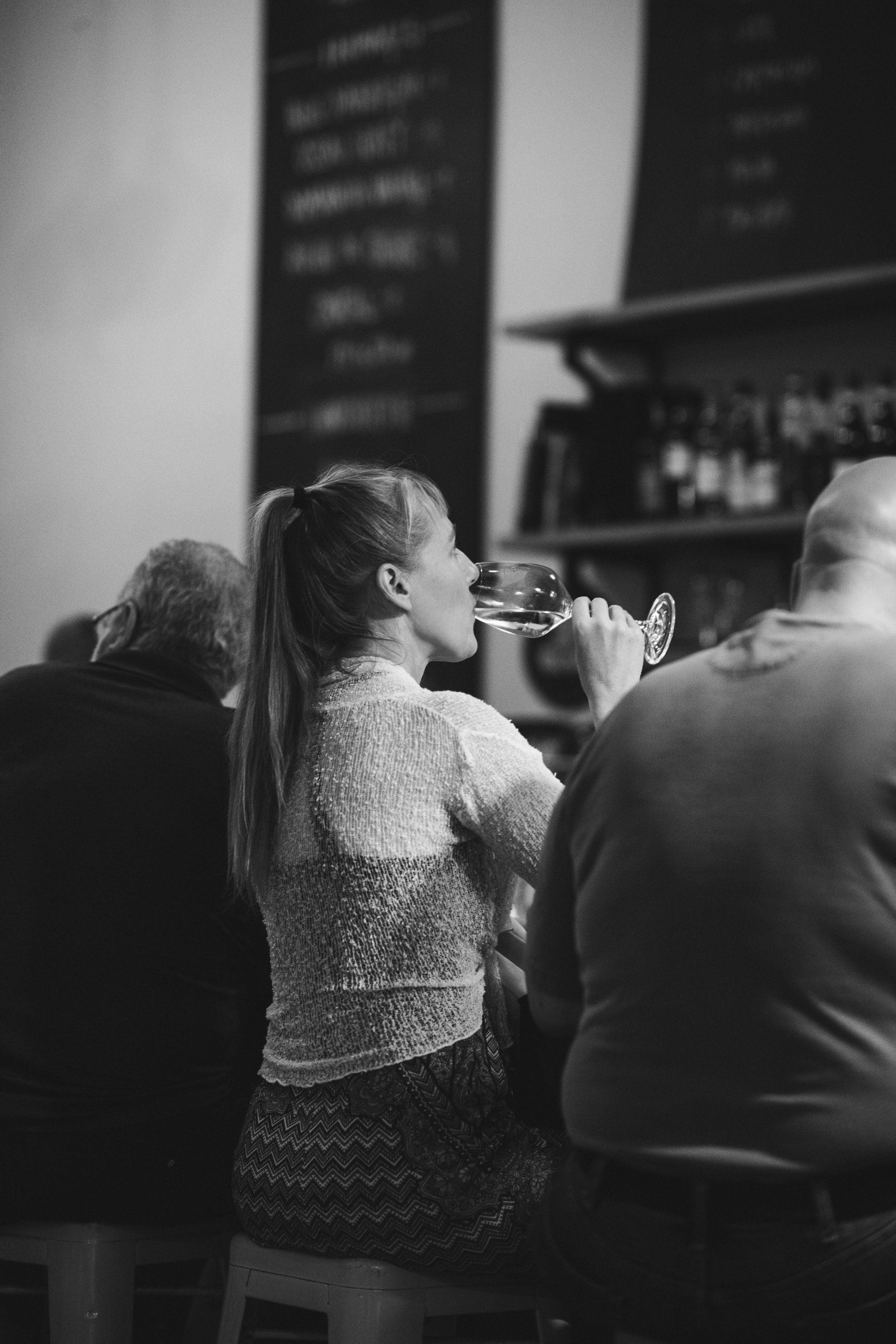 A woman is drinking a glass of wine in a black and white photo.