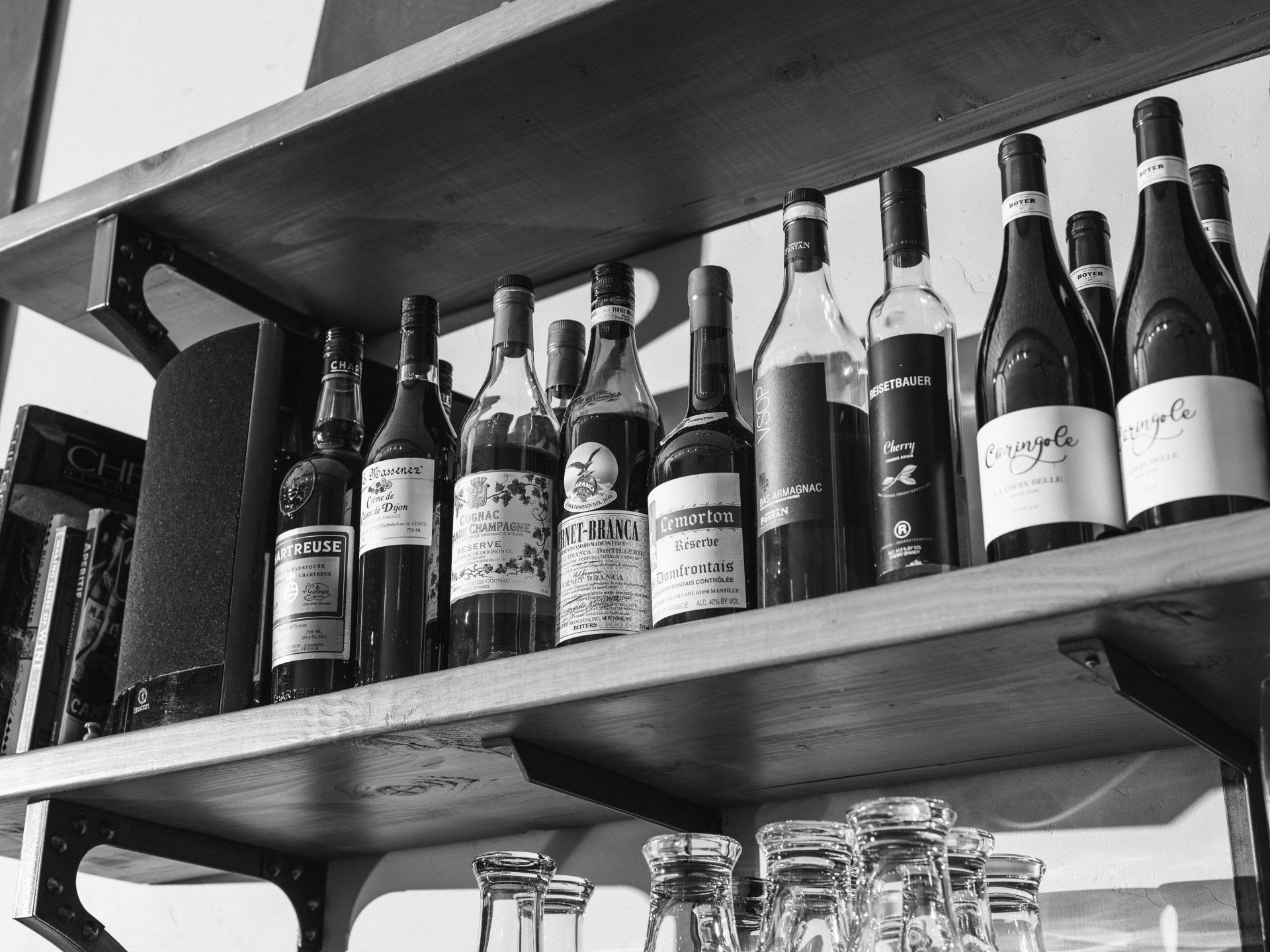 A black and white photo of wine bottles on a shelf