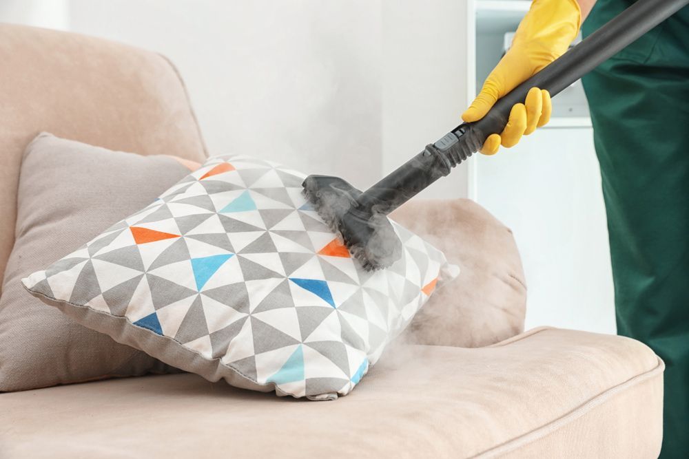 A Person Is Cleaning a Pillow on A Couch with A Steam Cleaner — Haydyn's Cleaning In Pialba, QLD