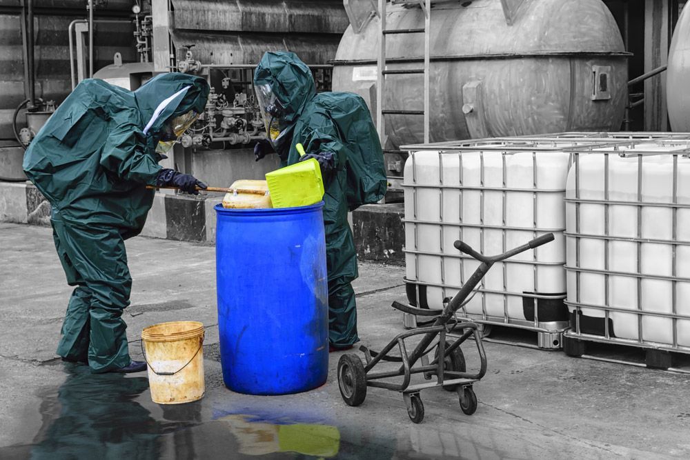 Two People in Protective Suits Are Cleaning a Blue Barrel in A Factory — Haydyn's Cleaning In Torquay, QLD