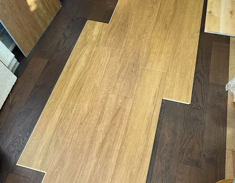 A section of light wood-tone flooring planks laid over a darker wooden floor.