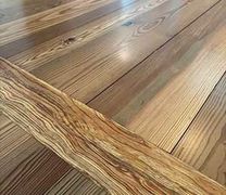 Close-up of wooden floor planks featuring a diagonal board with distinct, wavy, multi-toned wood grain patterns.
