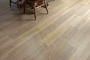 Light-toned hardwood flooring with visible wood grain, partially obscured by the wooden legs of a dining chair.
