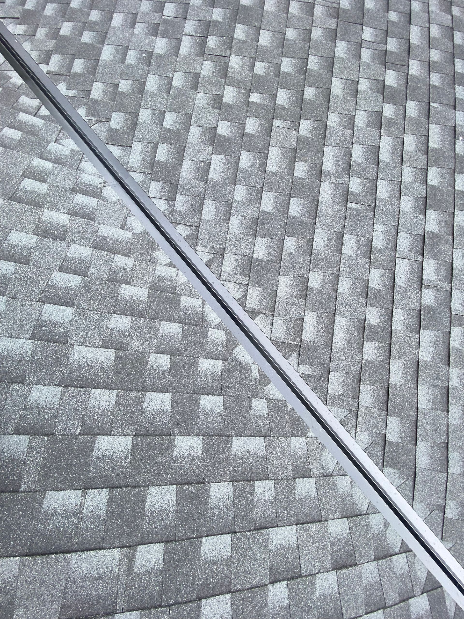Gray shingle roof with a silver metal strip running diagonally across it.