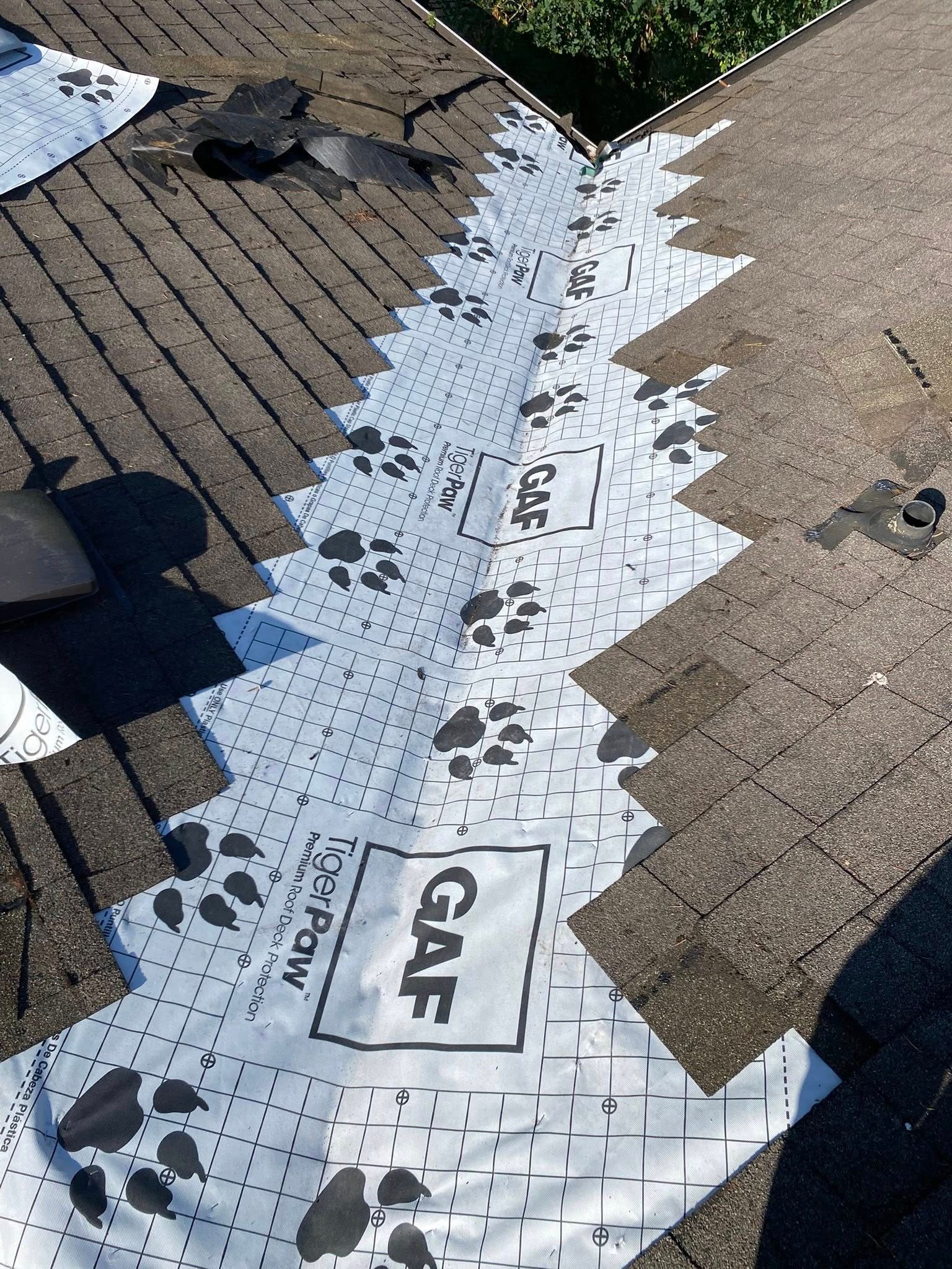 GAF-branded roofing underlayment, printed with paw prints, laid on a shingled roof, ready for installation.