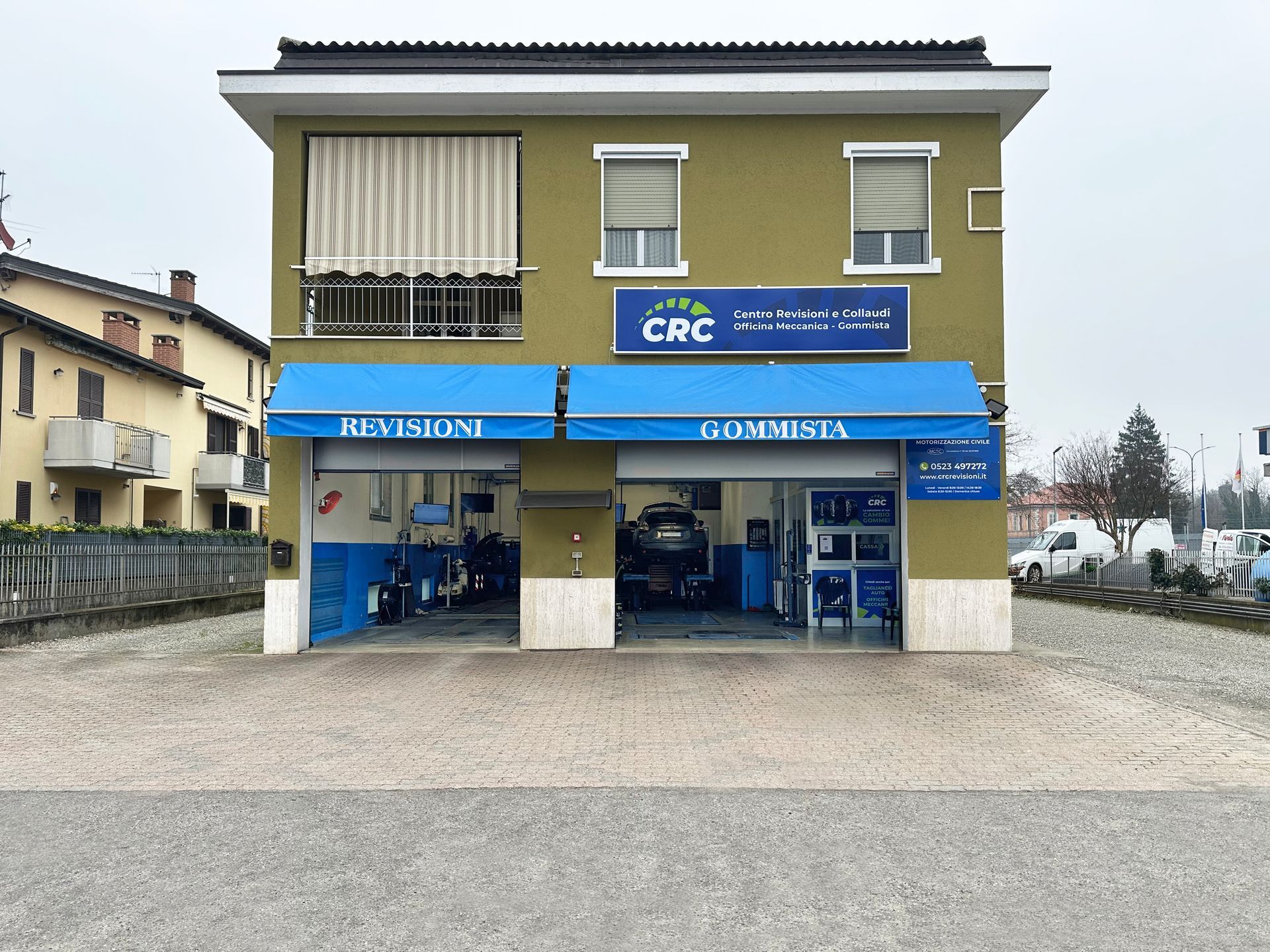 Due uomini lavorano su uno scooter all'interno di un garage. Uno è chino, l'altro è in piedi.