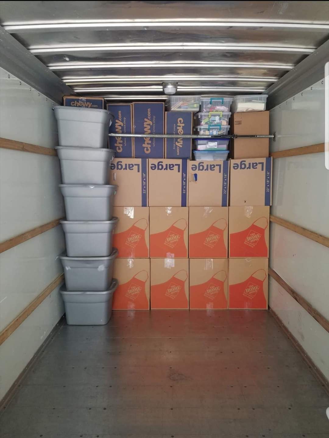 Inside a moving truck packed with gray bins and cardboard boxes of various sizes.