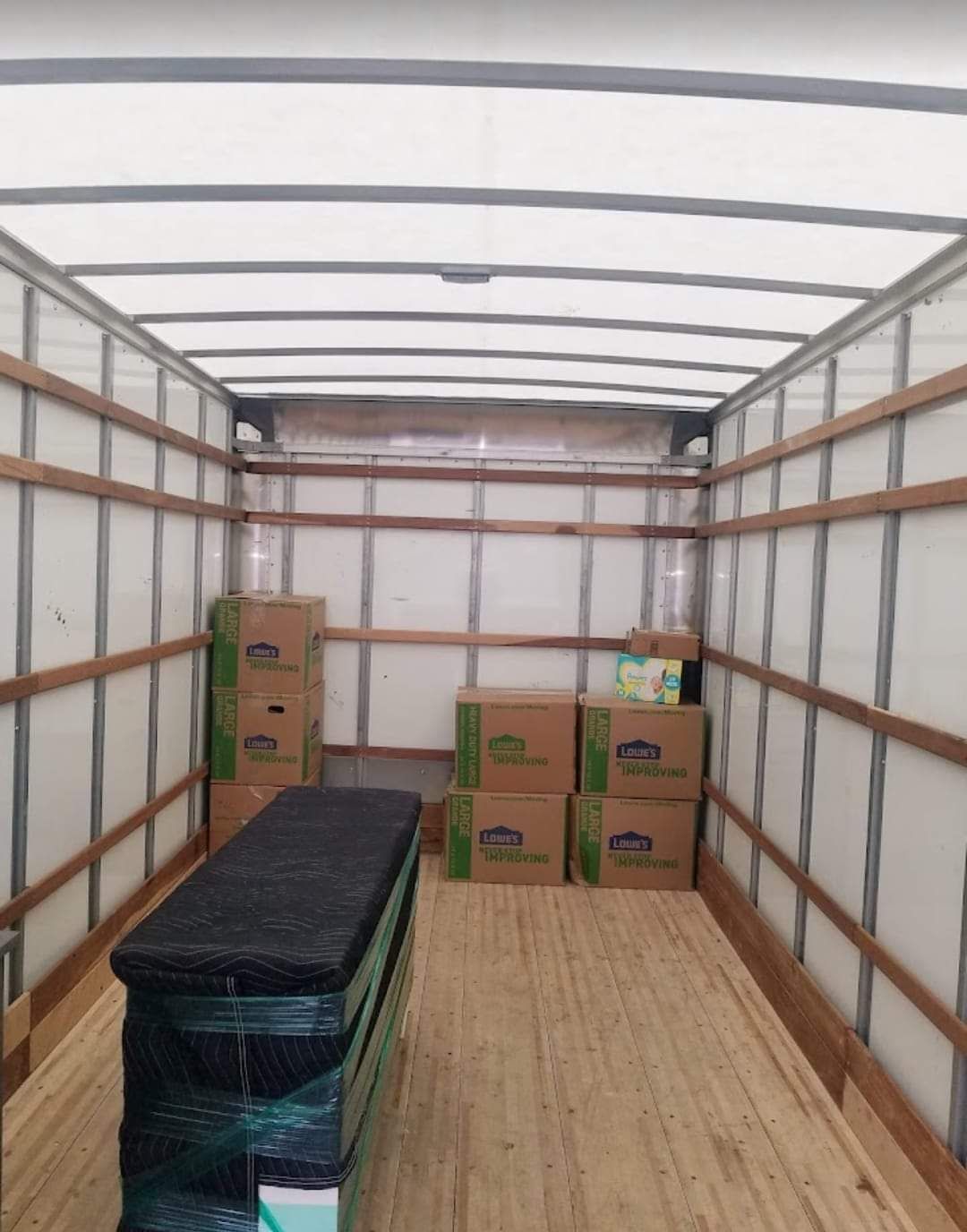 Inside of a moving truck with several boxes and a wrapped rectangular object.