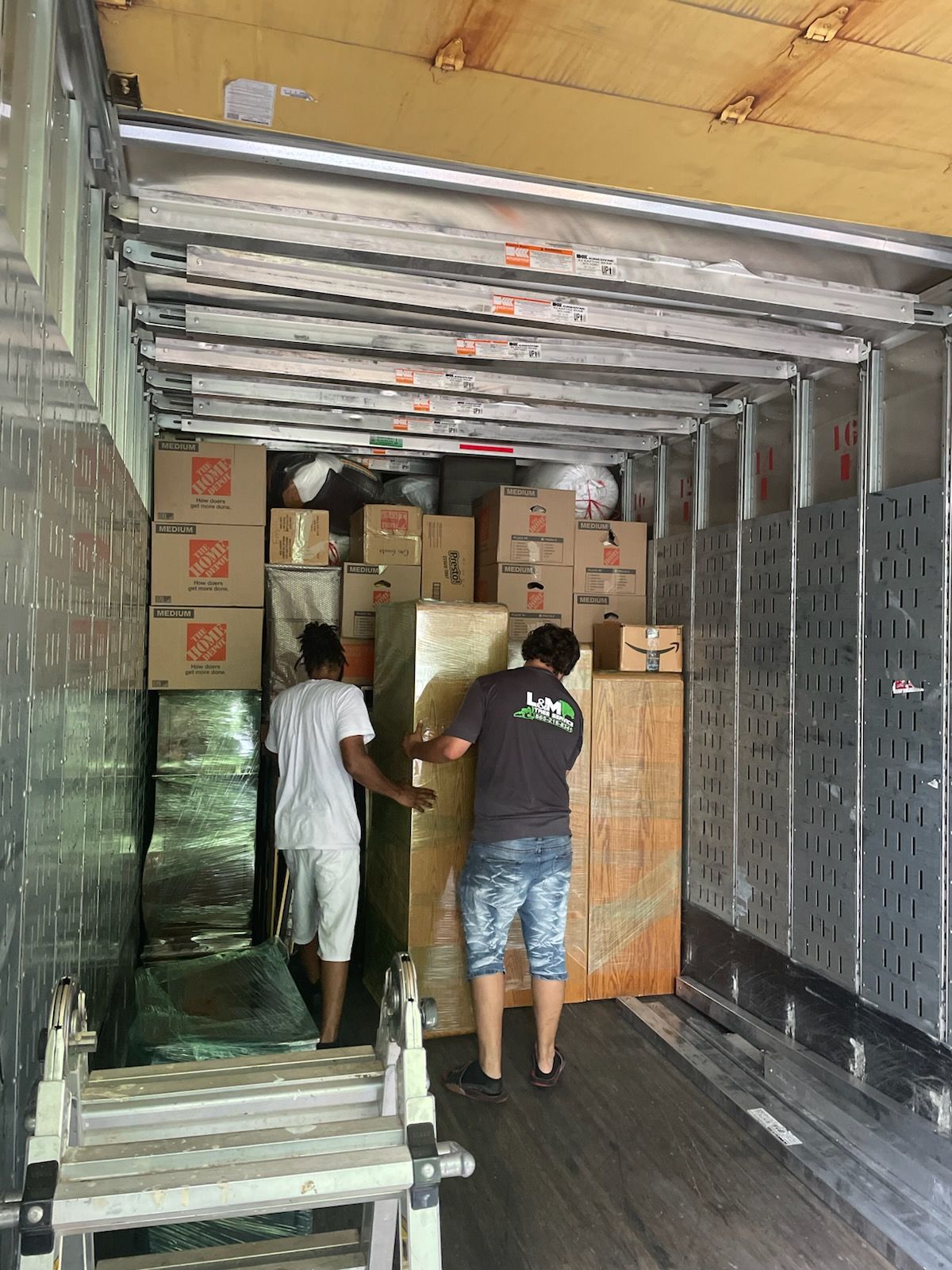 Two movers loading a packed truck with boxes and furniture.