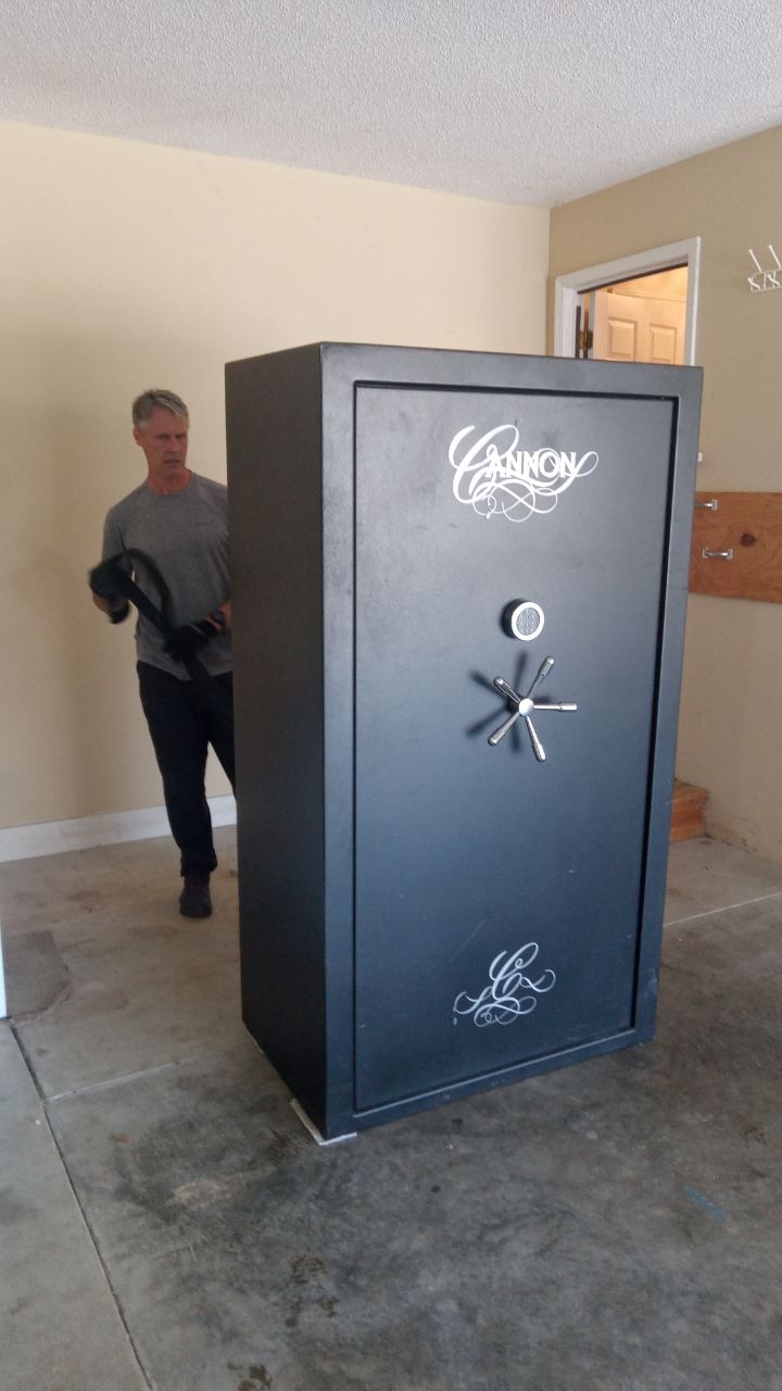 Man in garage next to a large, black Cannon safe.