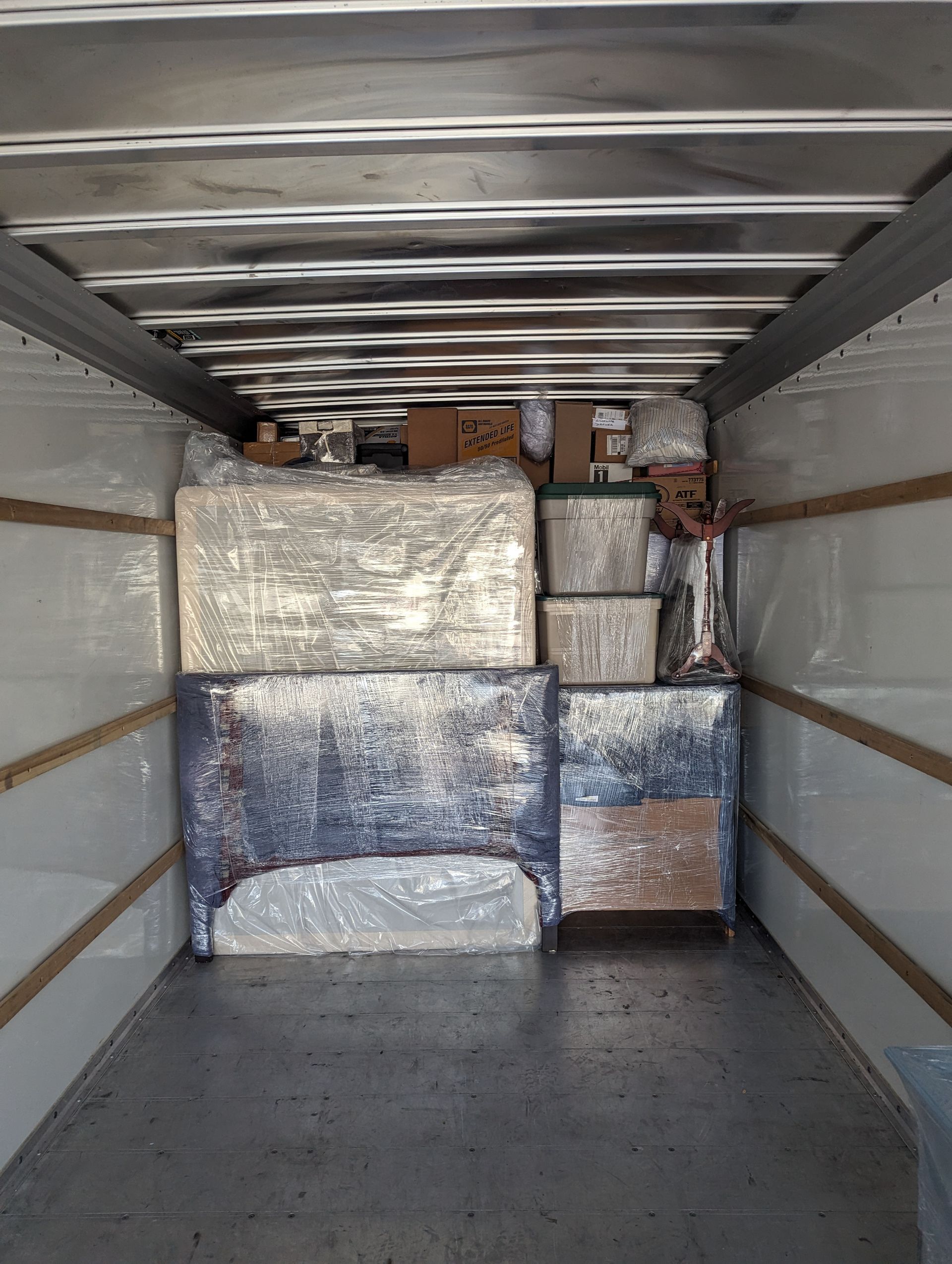 Inside a moving truck packed with wrapped furniture and boxes.