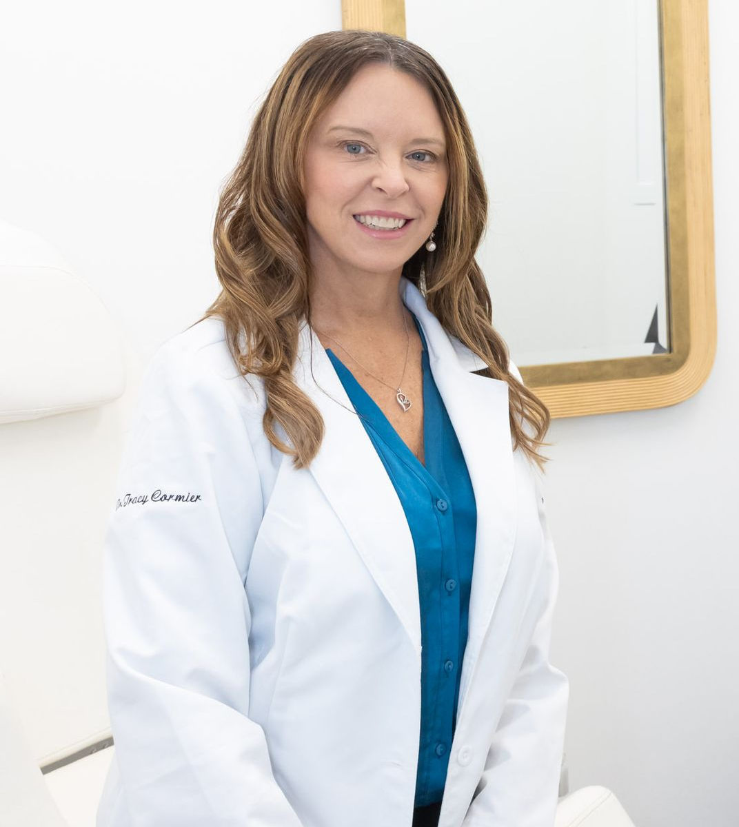 Doctor of TLC wearing a sweater and a heart necklace is smiling at the camera.