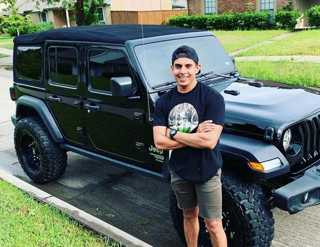 A man is standing in front of a black jeep.