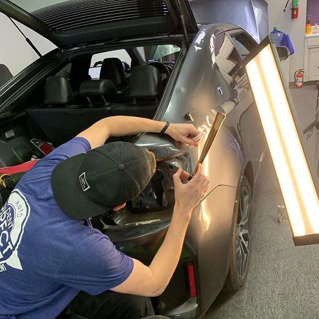 A man in a blue shirt is working on a car