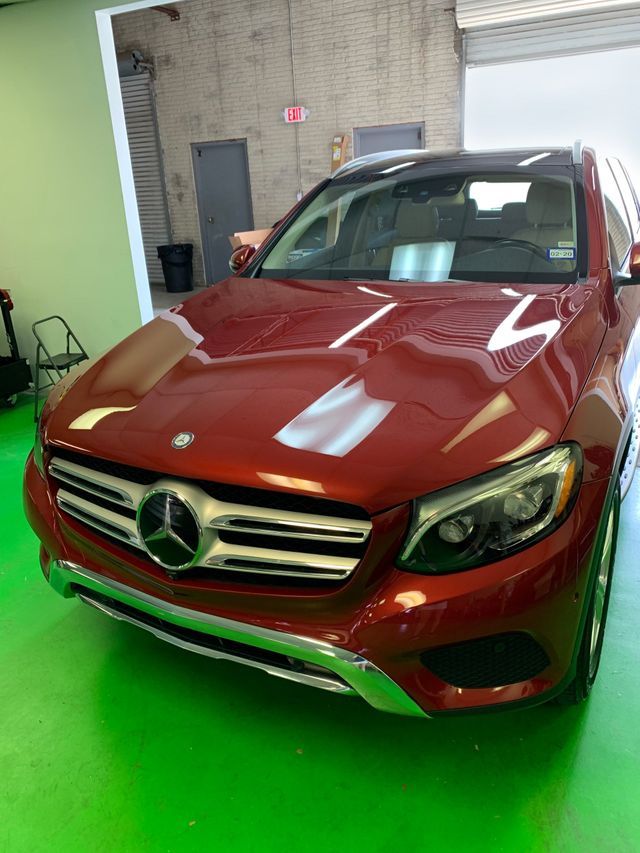 A red mercedes benz glc is parked in a green garage.