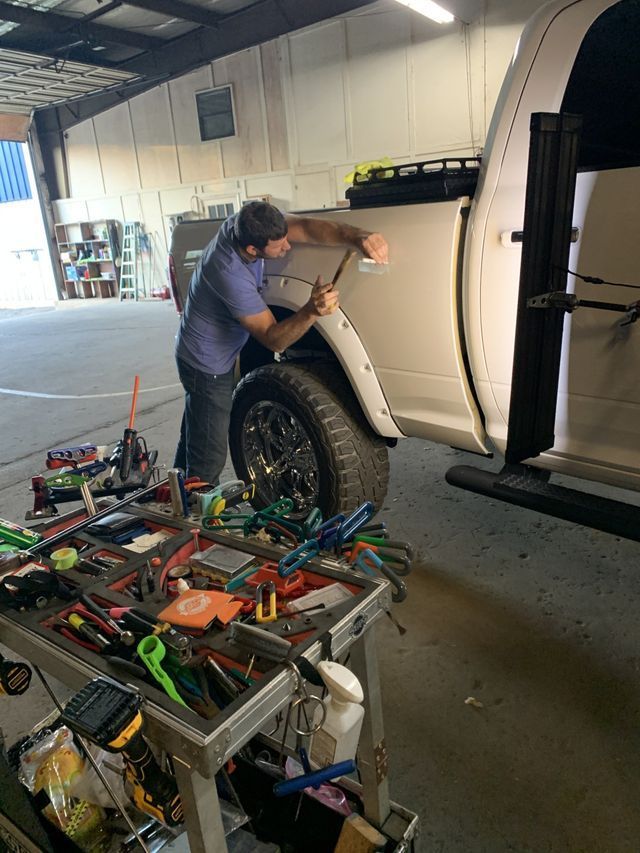 A man is working on the side of a truck in a garage.
