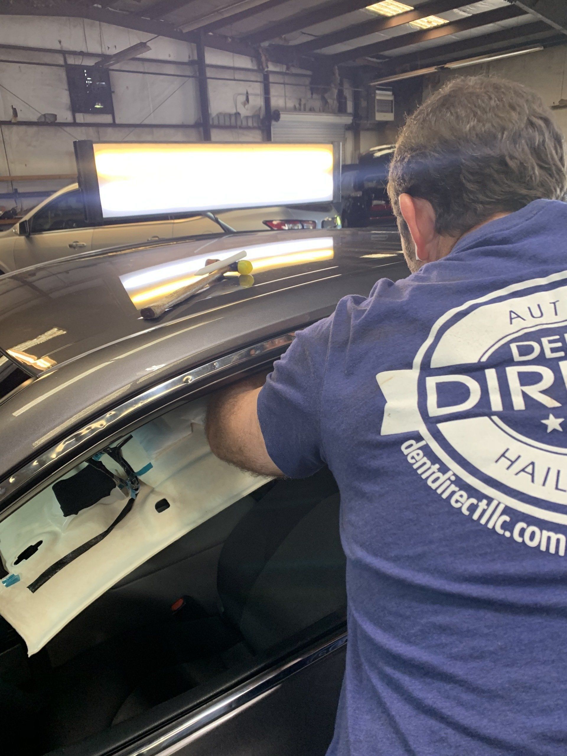 A man in a blue shirt is working on a car