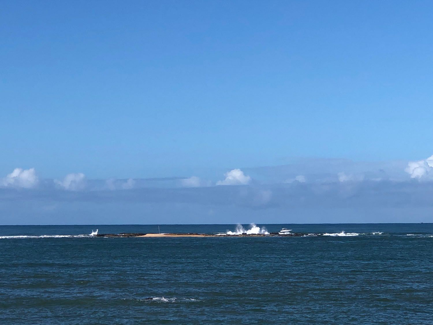 Um grande corpo de água com um céu azul ao fundo.
