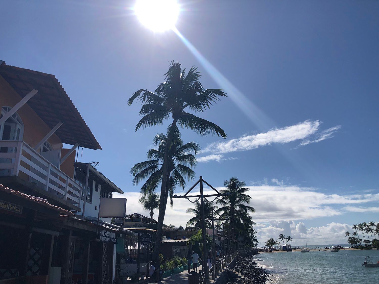 Uma casa com varanda com vista para um corpo d'água com palmeiras em primeiro plano