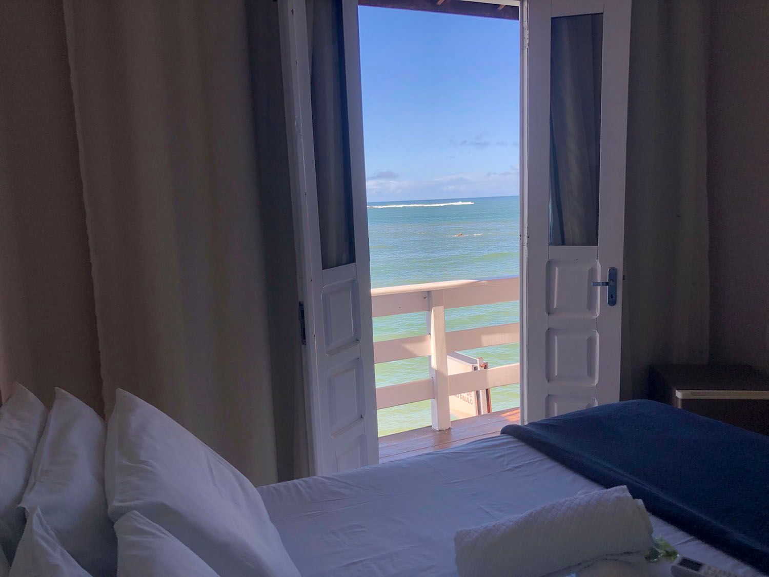 Um quarto com cama e varanda com vista para o mar.