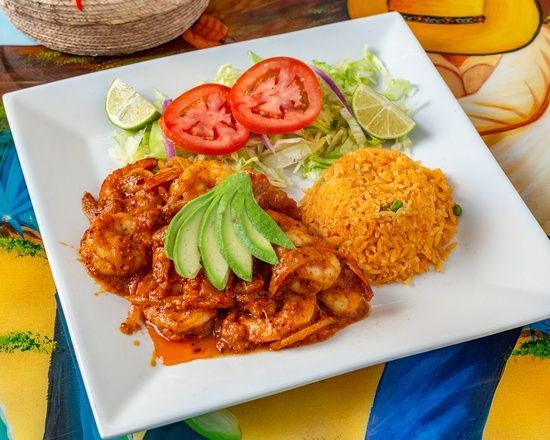 A white plate topped with shrimp , rice and avocado on a table.