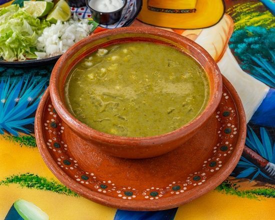 A bowl of soup is sitting on a plate on a table.