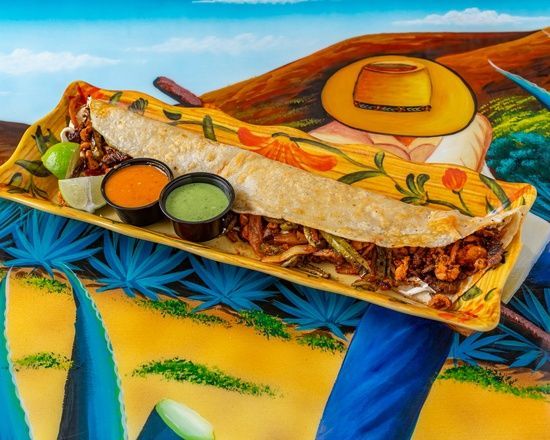 A person is holding a plate of food in front of a painting of a cowboy