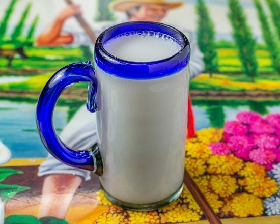 A glass of milk with a blue handle on a table
